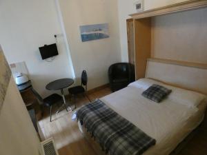 a bedroom with a bed and a desk and chairs at Hurst Dene Aparthotel in Swansea