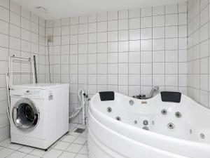 a bathroom with a white tub and a washing machine at Two-Bedroom Holiday home in Ringkøbing 10 in Dannemare