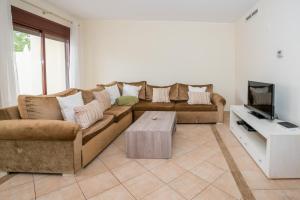 uma sala de estar com um sofá e uma televisão em Modern Vila Sol Townhouse with Traditional Vibes em Quarteira