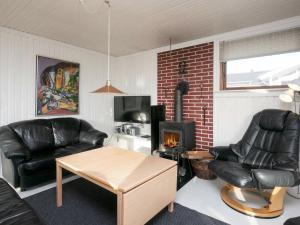 ファーボにあるThree-Bedroom Holiday home in Faaborg 3のリビングルーム(黒革の家具、暖炉付)
