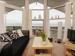 ein Wohnzimmer mit einem schwarzen Sofa und Meerblick in der Unterkunft 4 person holiday home in Otterup in Otterup
