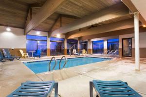- une piscine avec des chaises bleues dans un bâtiment dans l'établissement Days Inn by Wyndham Johnson Creek, à Johnson Creek