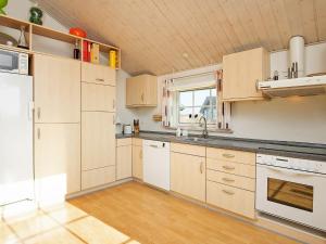 kuchnia z białymi szafkami i drewnianym sufitem w obiekcie 7 person holiday home in L kken w mieście Løkken