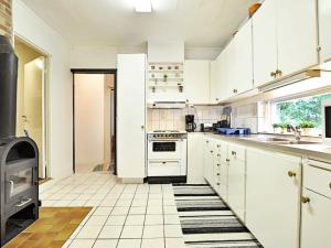 - une cuisine avec des placards blancs et une cuisinière dans l'établissement 5 person holiday home in H SSLEHOLM, à Hässleholm