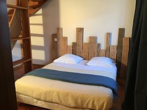 - une chambre avec un grand lit et une tête de lit en bois dans l'établissement Au mohair des Alpy, à Fougax-et-Barrineuf