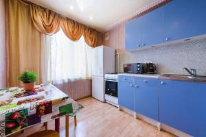 モスクワにあるApartment Hanaka Shchelkovskoye 77のキッチン(青いキャビネット、シンク付きテーブル付)