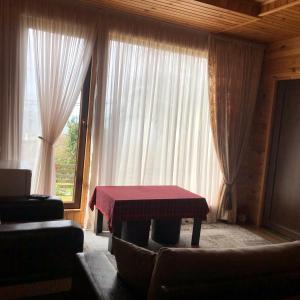 ein Wohnzimmer mit einem Tisch vor einem Fenster in der Unterkunft Chalet Ochos Qokhi in Kwariati