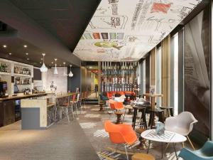 a restaurant with orange chairs and a bar at ibis London Excel-Docklands in London