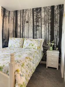 a bedroom with a bed with a forest wallpaper at Studio 95 in Kirkby Lonsdale