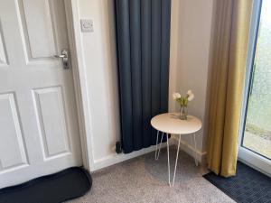 a table next to a door with a vase of flowers on it at Studio 95 Kirkby Lonsdale in Kirkby Lonsdale