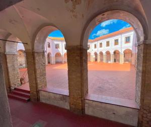 a view of a courtyard through the archways of a building at B&B Chiostro San Marco in Tarquinia