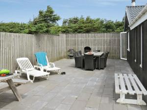 een patio met stoelen, een tafel en een hek bij 10 person holiday home in Harbo re in Harboør