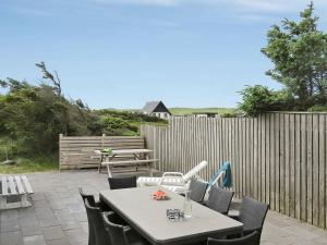 eine Terrasse mit einem Tisch, Stühlen und einem Zaun in der Unterkunft 10 person holiday home in Harbo re in Harboør