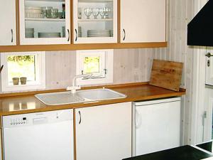 ホーンバックにある6 person holiday home in Dronningm lleの白いキャビネットとシンク付きのキッチン