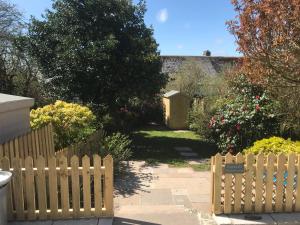 a wooden fence in a garden with flowers at Frogmore Corner in Tregoney