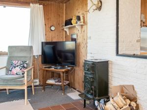 a living room with a television and a chair at 6 person holiday home in Henne in Henne Strand