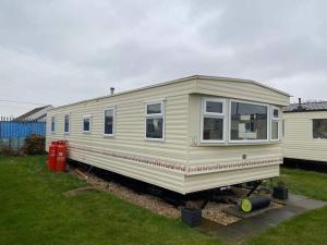 a yellow tiny house sitting in a yard at 8 Berth Sealands (Highbury) in Ingoldmells