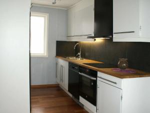 a kitchen with white cabinets and black appliances at 4 person holiday home in H CKSVIK in Håcksvik