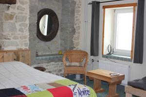 1 dormitorio con cama, silla y espejo en Maison le Barrage, en Saint-Gervais-dʼAuvergne