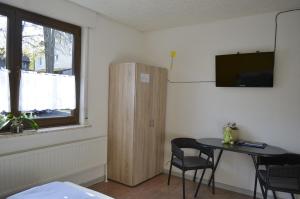 a room with a table and a cabinet and a window at Sunrise B&B Hellenthal in Hellenthal
