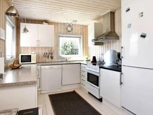 ロンストラップにある6 person holiday home in Hj rringの白い家電製品と木製の壁が備わるキッチン