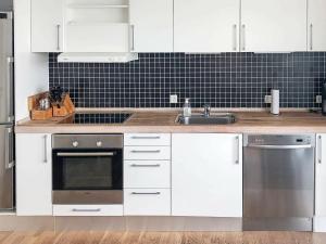 HejlsにあるHoliday Home Banedæmningen IIの白いキャビネット、シンク、食器洗い機付きのキッチンが備わります。