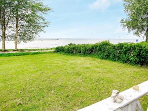 a white fence with a field of grass and the ocean at 8 person holiday home in Gelting in Gelting