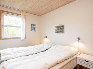 Cette chambre comprend un grand lit blanc et une fenêtre. dans l'établissement Holiday home Læsø XXIV, à Læsø