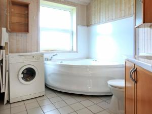 een badkamer met een bad en een wasmachine bij 12 person holiday home in Otterndorf in Otterndorf