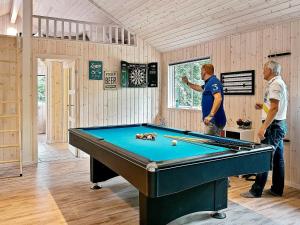two men standing in a room with a pool table at 16 person holiday home in Dronningm lle in Gilleleje