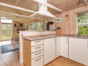 Jerupにある5 person holiday home in Jerupの白いキャビネットと木製の天井が備わるキッチン