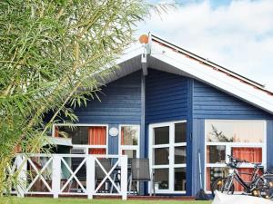 ein blaues Haus mit weißen Fenstern und einem Fahrrad, das draußen geparkt ist in der Unterkunft 6 person holiday home in Otterndorf in Otterndorf
