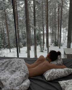 a naked woman laying on a bed in the woods at Greenvald Park Scandinavia in Ogon'ki