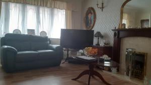 ein Wohnzimmer mit einem Sofa und einem TV in der Unterkunft the brier house in Swadlincote