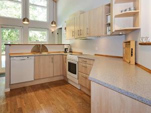 a large kitchen with white appliances and wooden cabinets at 6 person holiday home in Hadsund in Odde