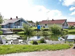 a house next to a lake with chairs and a table at 6 person holiday home in Otterndorf in Otterndorf