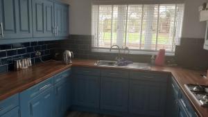 una cocina con armarios azules y fregadero en the brier house, en Swadlincote