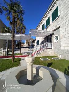 a cross in front of a building with a palm tree at Hotel Stolac in Stolac