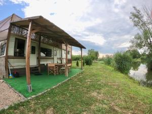 a caravan with a porch and a table on the grass at Honey Tiny Home in Vadu Crişului
