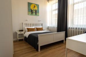 a white bedroom with a bed and two windows at Beautiful apartment in the heart of Kaunas in Kaunas