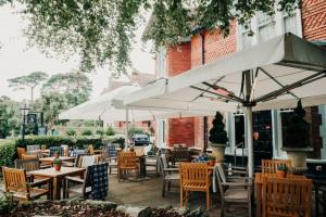 an outdoor patio with tables and chairs and umbrellas at Inn in the Park in Bournemouth