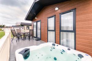 a jacuzzi tub on the deck of a house at Woodpecker Lodge with Hot Tub in York