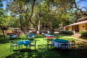 een groep tafels en stoelen in het gras bij Adamo The Village in Matheran