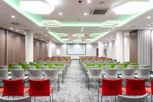 una sala de conferencias con sillas rojas y luces verdes en ibis Styles Lublin Stare Miasto, en Lublin