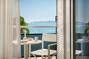 balcón con mesa, sillas y vistas al océano en Hotel Marina - Liburnia en Mošćenička Draga