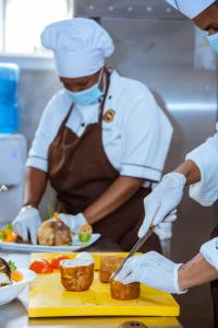 due chef in una cucina che preparano il cibo su un tagliere di Le Ndiambour Hôtel et Résidence a Dakar