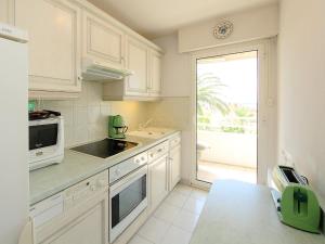 a kitchen with white cabinets and a large window at Apartment Riviera Park by Interhome in Cannes
