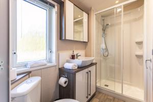 uma casa de banho com um WC, um lavatório e um chuveiro em Lakeshore Lodge with Hot Tub em Pocklington