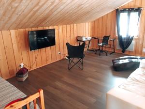 een woonkamer met stoelen en een televisie in een cabine bij Chez Siouab in Saint-Hostien