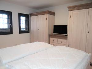 a bedroom with a white bed and a flat screen tv at Speicher Residenz Barth E4 App 9 in Barth